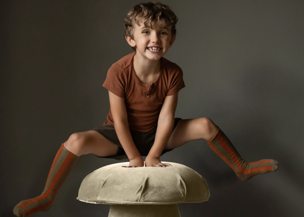 A boy jumping over a Velvet Mushroom Stool in Camel